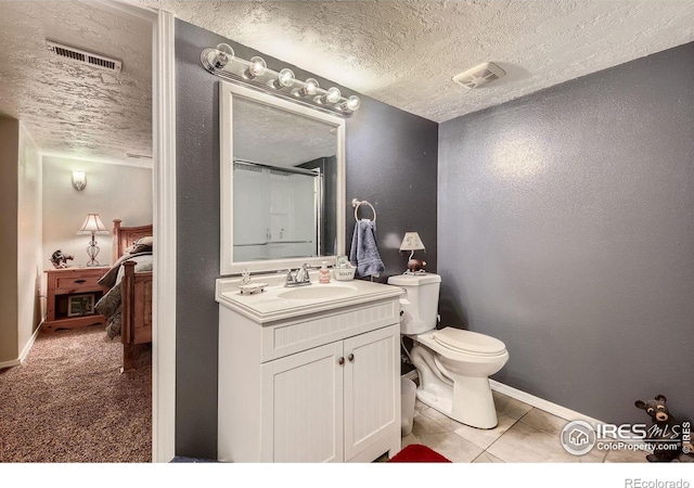 bathroom with tile patterned flooring, vanity, walk in shower, toilet, and a textured ceiling