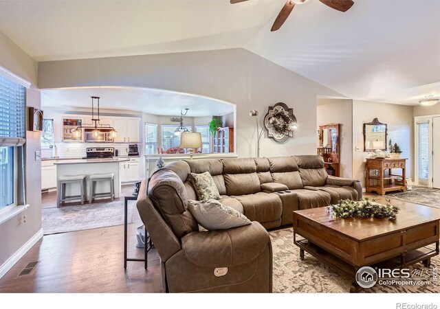 living room with hardwood / wood-style floors, vaulted ceiling, and ceiling fan