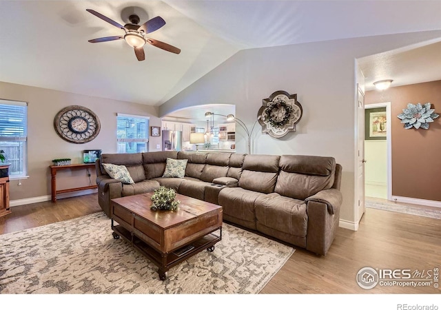 living room featuring lofted ceiling, ceiling fan, and light wood-type flooring