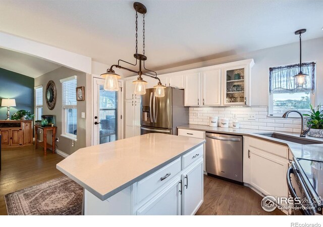 kitchen featuring sink, white cabinetry, appliances with stainless steel finishes, a kitchen island, and pendant lighting