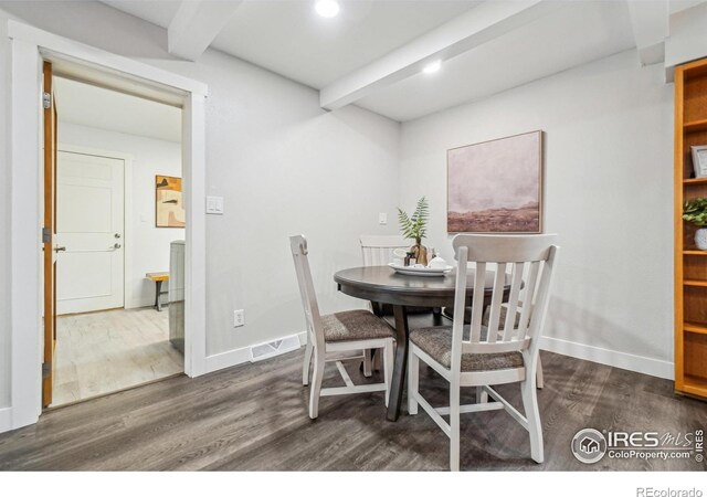 dining space with beamed ceiling and dark wood-type flooring