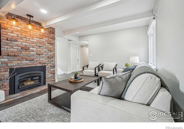 living room with beamed ceiling, a brick fireplace, and hardwood / wood-style flooring