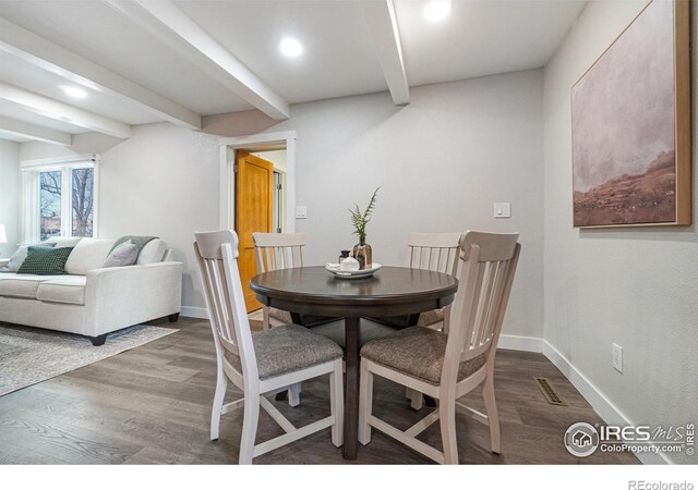 dining area with dark hardwood / wood-style flooring and beam ceiling