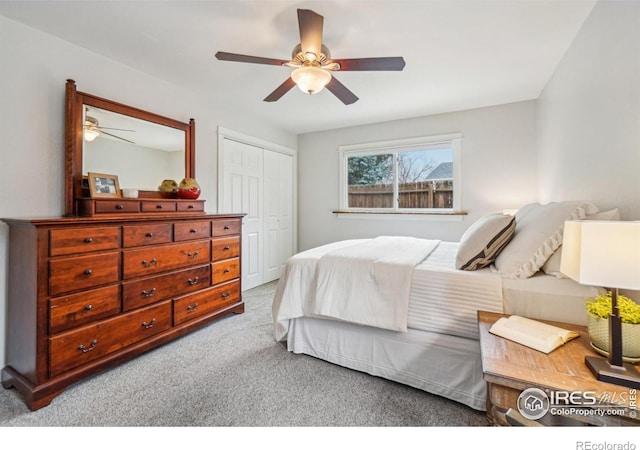 bedroom featuring light colored carpet, ceiling fan, and a closet