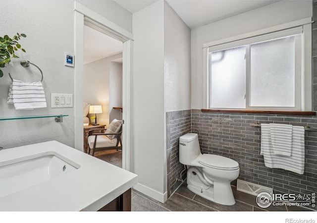 bathroom featuring vanity, tile patterned floors, tile walls, and toilet