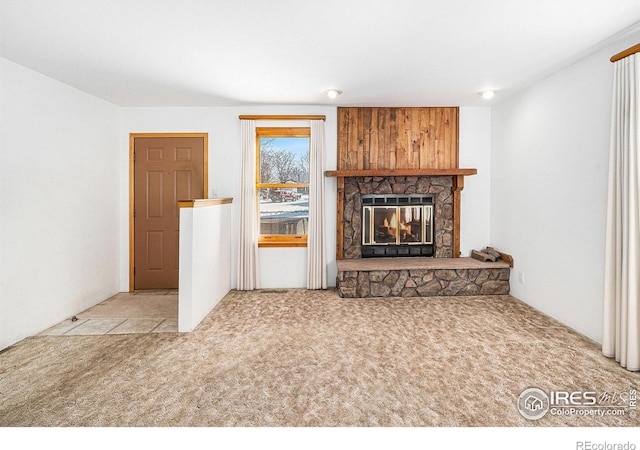 unfurnished living room with light colored carpet and a stone fireplace