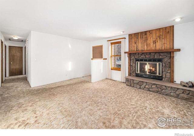 unfurnished living room featuring a stone fireplace and light colored carpet