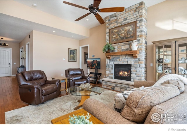 living room with a stone fireplace, hardwood / wood-style floors, and ceiling fan