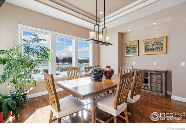 dining space featuring crown molding, dark hardwood / wood-style flooring, and a raised ceiling