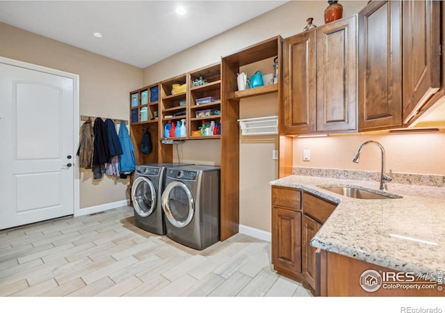 laundry room with cabinets, independent washer and dryer, light hardwood / wood-style floors, and sink