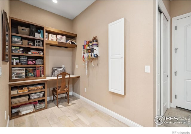 home office with built in desk and light wood-type flooring