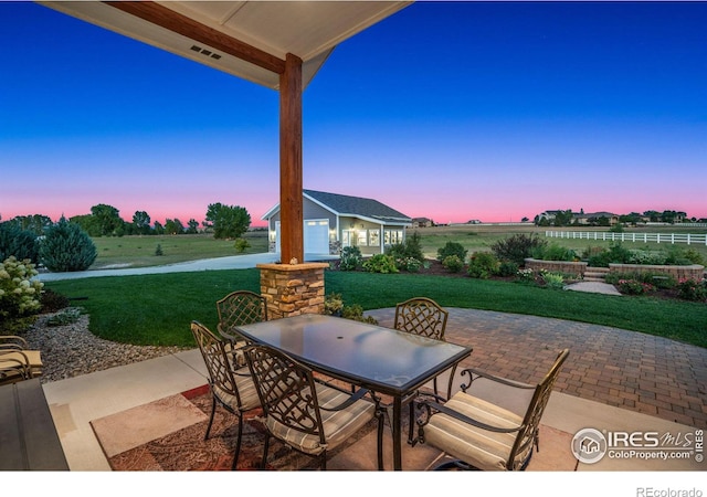 patio terrace at dusk featuring an outdoor structure and a lawn