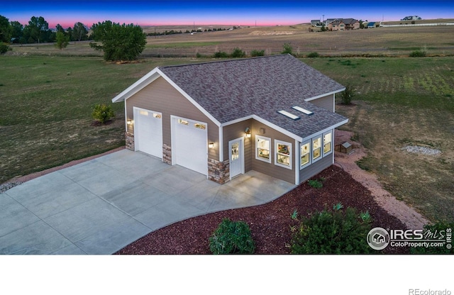 view of front of property featuring a garage and a rural view