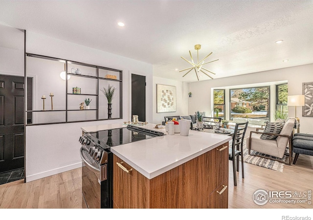 kitchen with light hardwood / wood-style flooring, an inviting chandelier, a textured ceiling, a kitchen island, and stainless steel range with electric cooktop