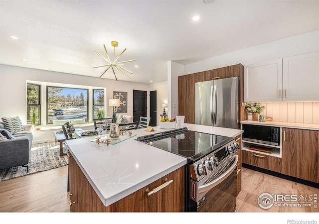 kitchen featuring stainless steel appliances, a kitchen island, open floor plan, and light countertops