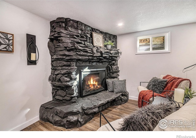 living room with wood finished floors, a fireplace, baseboards, and a textured ceiling