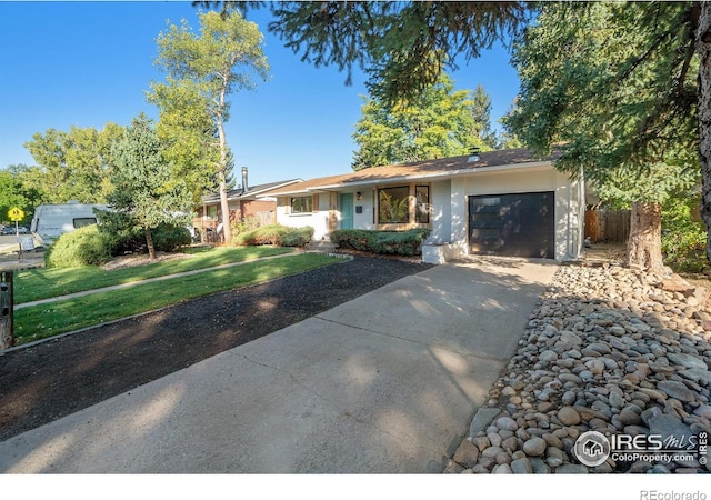 ranch-style home featuring stucco siding, a front yard, an attached garage, and driveway