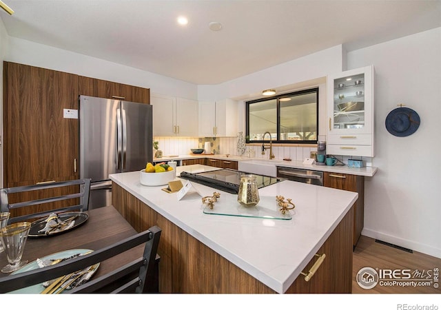 kitchen with white cabinetry, appliances with stainless steel finishes, a center island, and light countertops