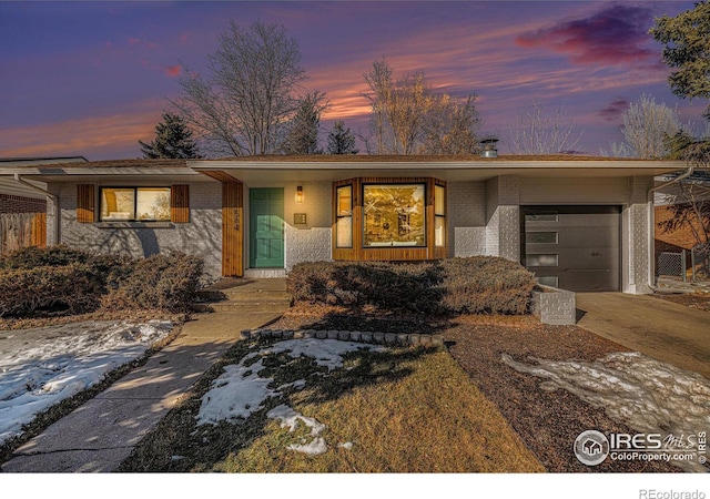 mid-century inspired home featuring a garage, brick siding, and concrete driveway