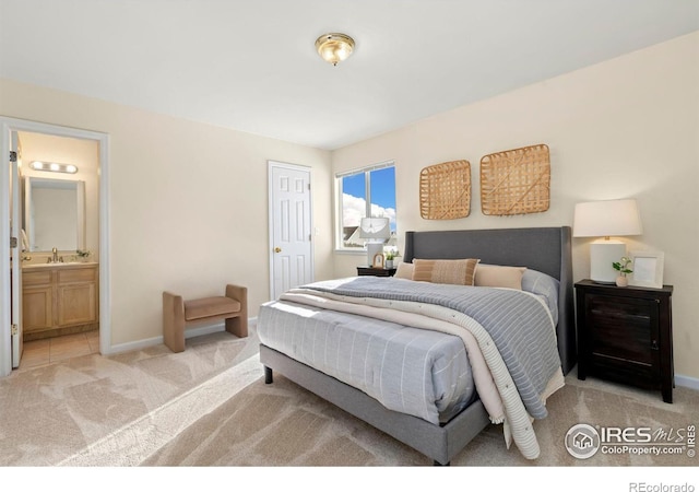 bedroom with light colored carpet, sink, and ensuite bath