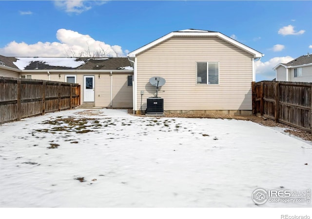 snow covered rear of property featuring central AC