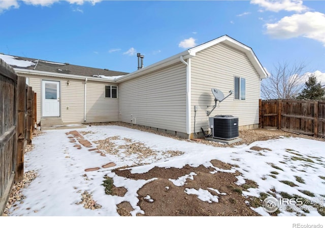 snow covered rear of property with central AC unit