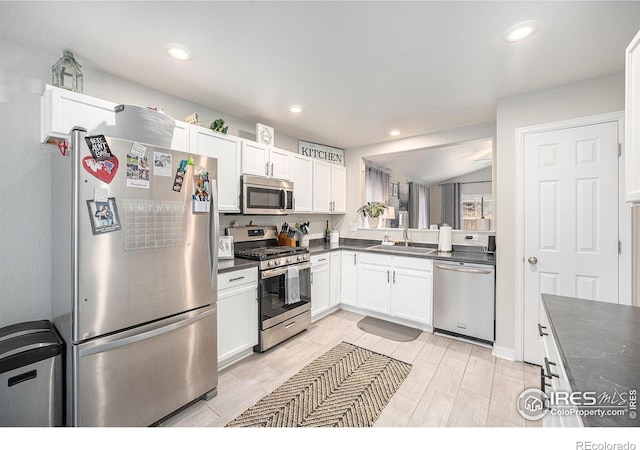 kitchen featuring white cabinetry, lofted ceiling, appliances with stainless steel finishes, and sink