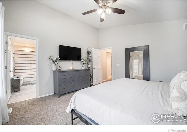 bedroom featuring lofted ceiling, light carpet, connected bathroom, and ceiling fan