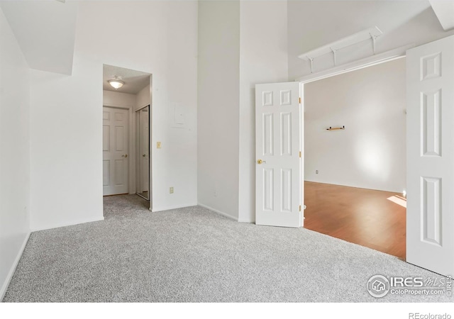 spare room with a towering ceiling and carpet flooring