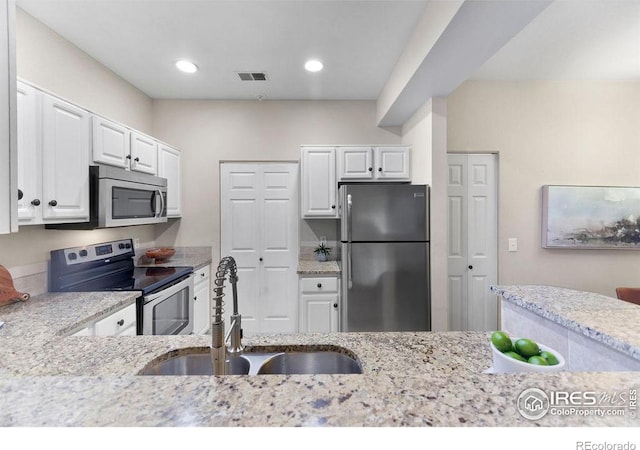 kitchen featuring stainless steel appliances, light stone countertops, sink, and white cabinets