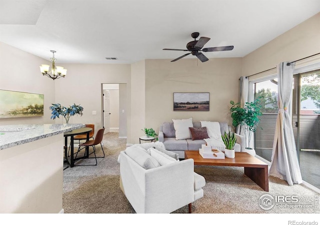 carpeted living room featuring ceiling fan with notable chandelier