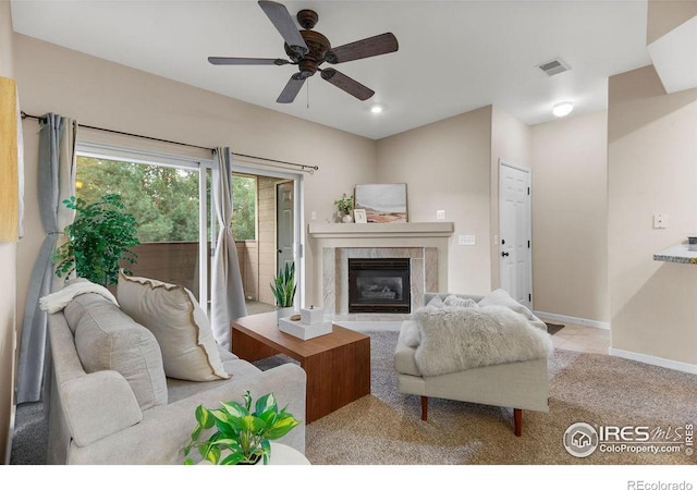 living room featuring light carpet, a fireplace, and ceiling fan