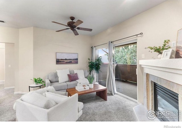 living room with light carpet, a premium fireplace, and ceiling fan