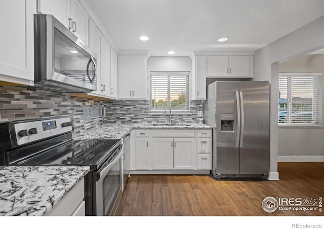 kitchen featuring sink, stainless steel appliances, white cabinets, and light stone countertops