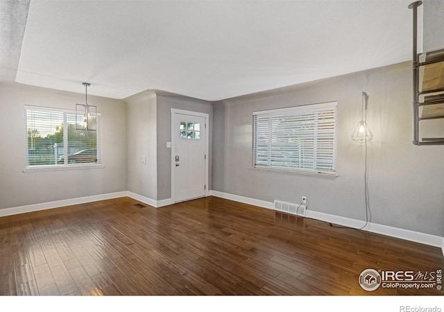 foyer entrance with dark hardwood / wood-style flooring and a chandelier