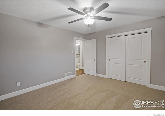 unfurnished bedroom with light colored carpet, ceiling fan, and a closet