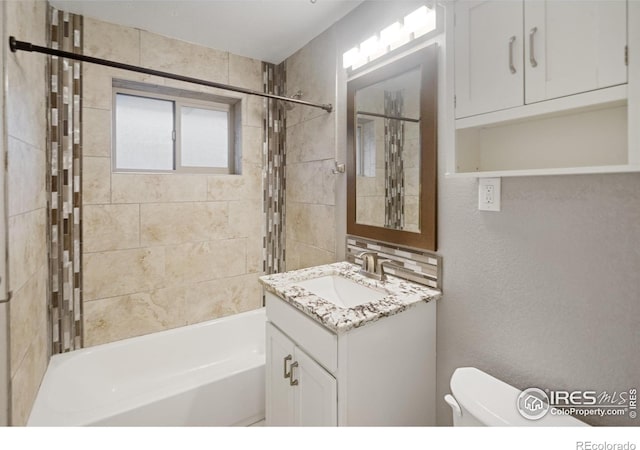 full bathroom featuring tiled shower / bath, vanity, and toilet