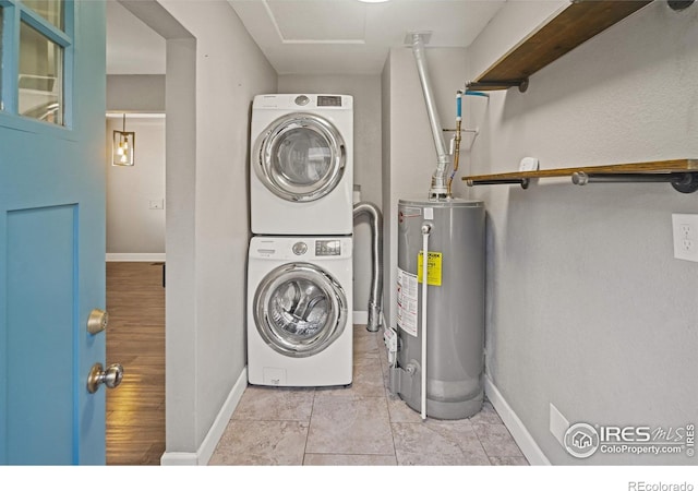 clothes washing area featuring stacked washer / drying machine and water heater