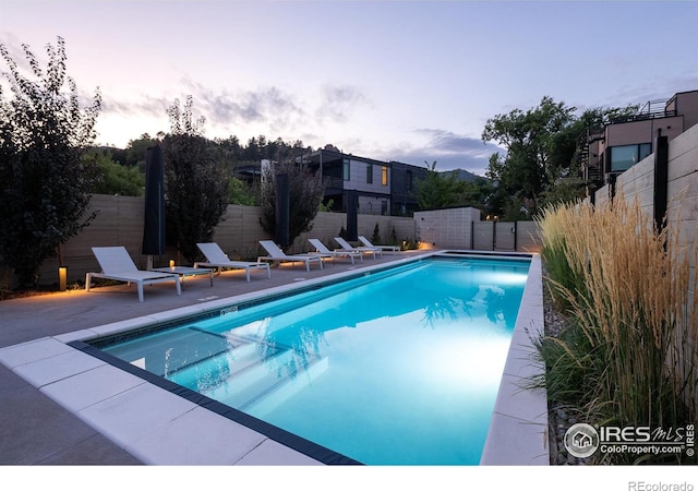 pool at dusk featuring a patio