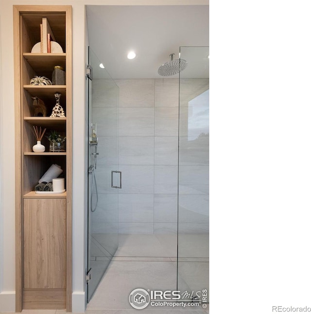 bathroom with built in shelves and a shower with door