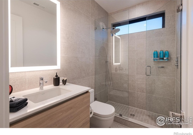 bathroom featuring toilet, an enclosed shower, tile walls, vanity, and decorative backsplash