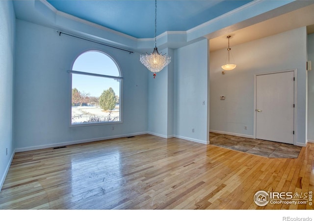 spare room with a notable chandelier, light hardwood / wood-style flooring, and ornamental molding