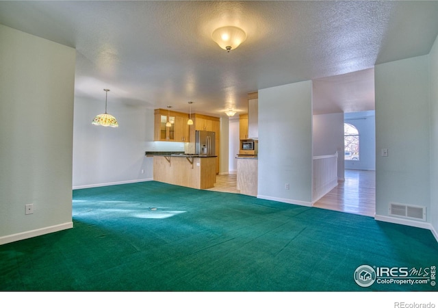 unfurnished living room featuring dark carpet and a textured ceiling