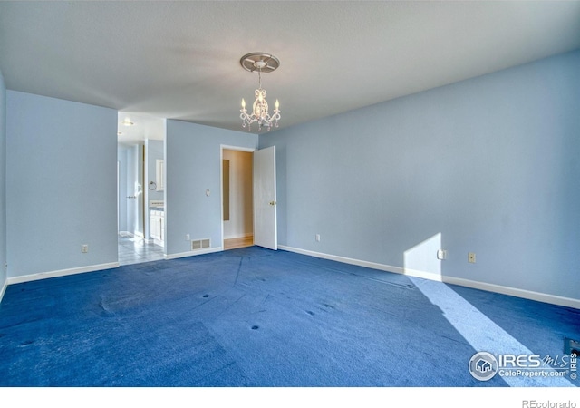 unfurnished room featuring a chandelier and dark carpet