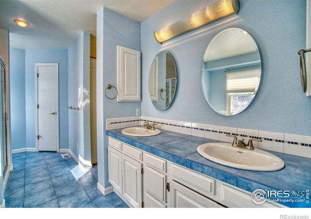 bathroom featuring tile patterned floors, vanity, and a shower with door