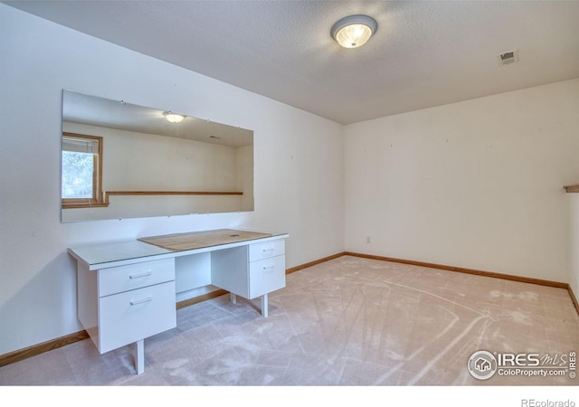 unfurnished office featuring light colored carpet and a textured ceiling