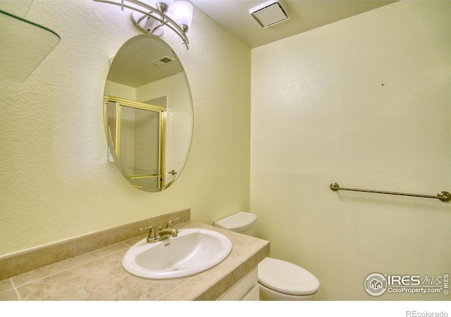 bathroom featuring vanity, toilet, and an enclosed shower