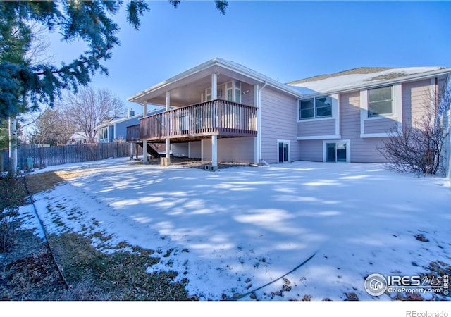 snow covered back of property with a deck