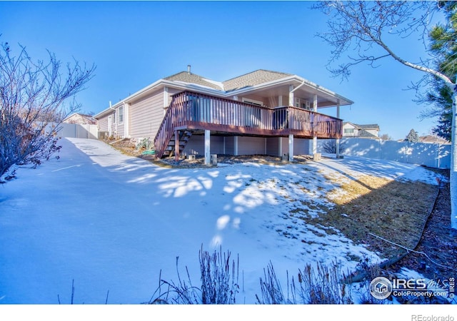 snow covered rear of property featuring a wooden deck