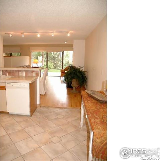 kitchen with dishwasher, light tile patterned floors, a textured ceiling, and white cabinets